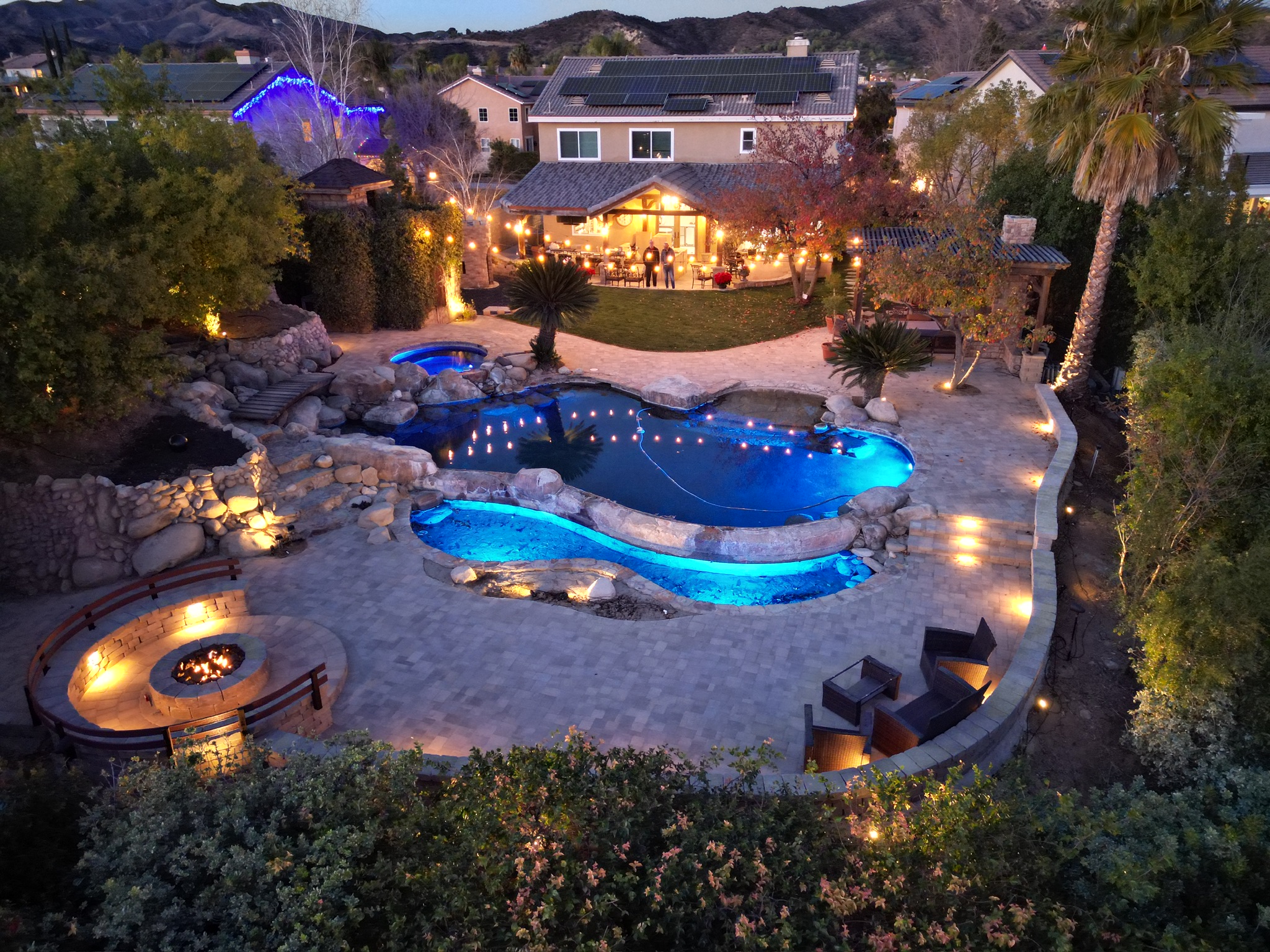 Resort-style backyard with freeform pool and fire pit — drone shot